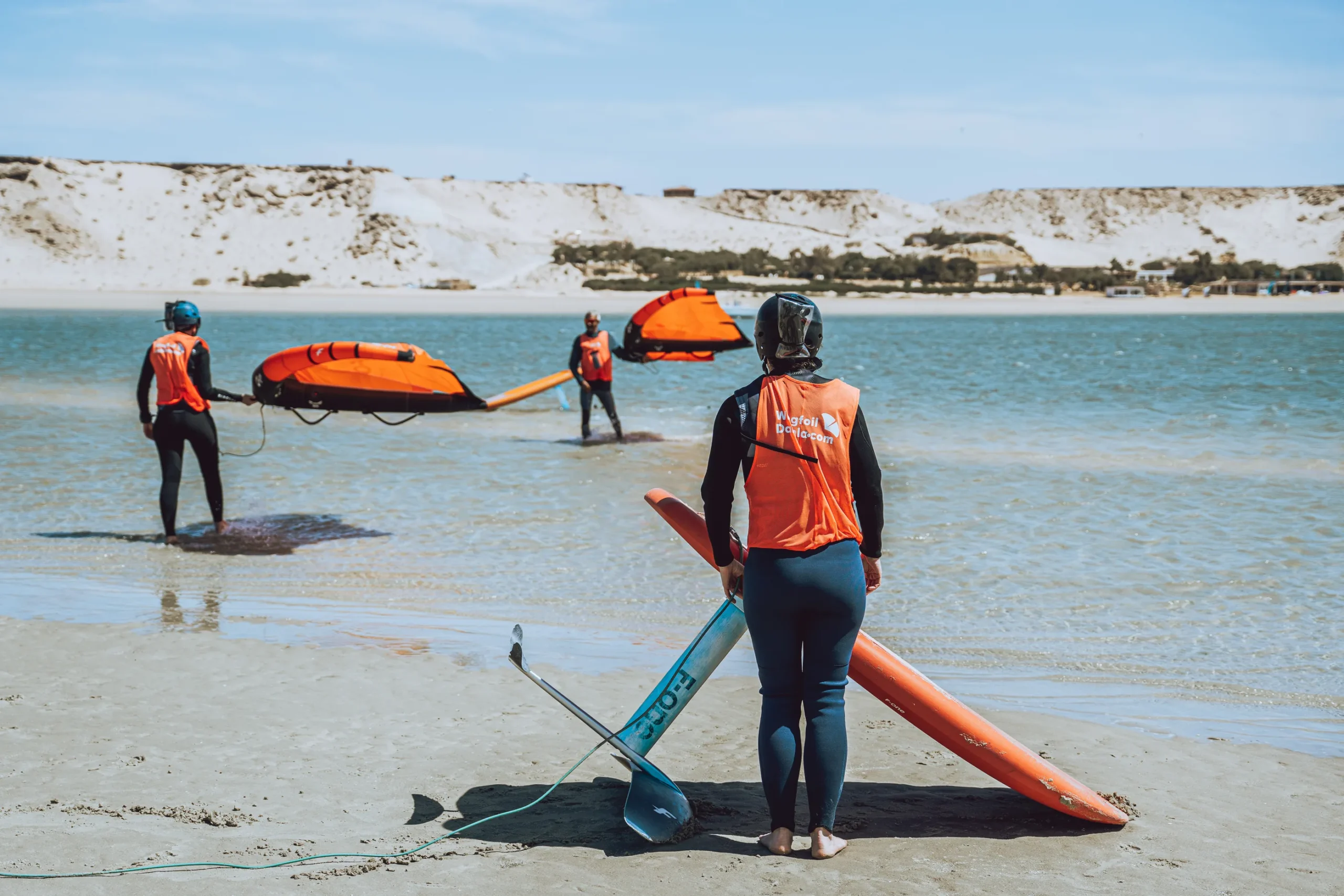 Cours de wingfoil à Dakhla – élève se préparant à entrer dans l’eau avec planche et aile