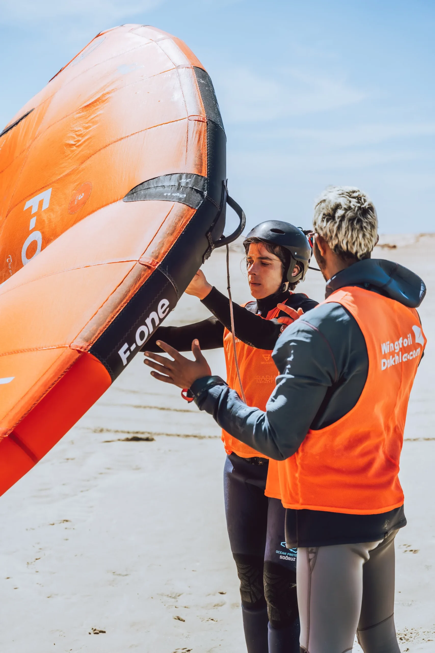 Cours de wingfoil à Dakhla avec moniteur corrigeant la position de l’aile pour un élève débutant
