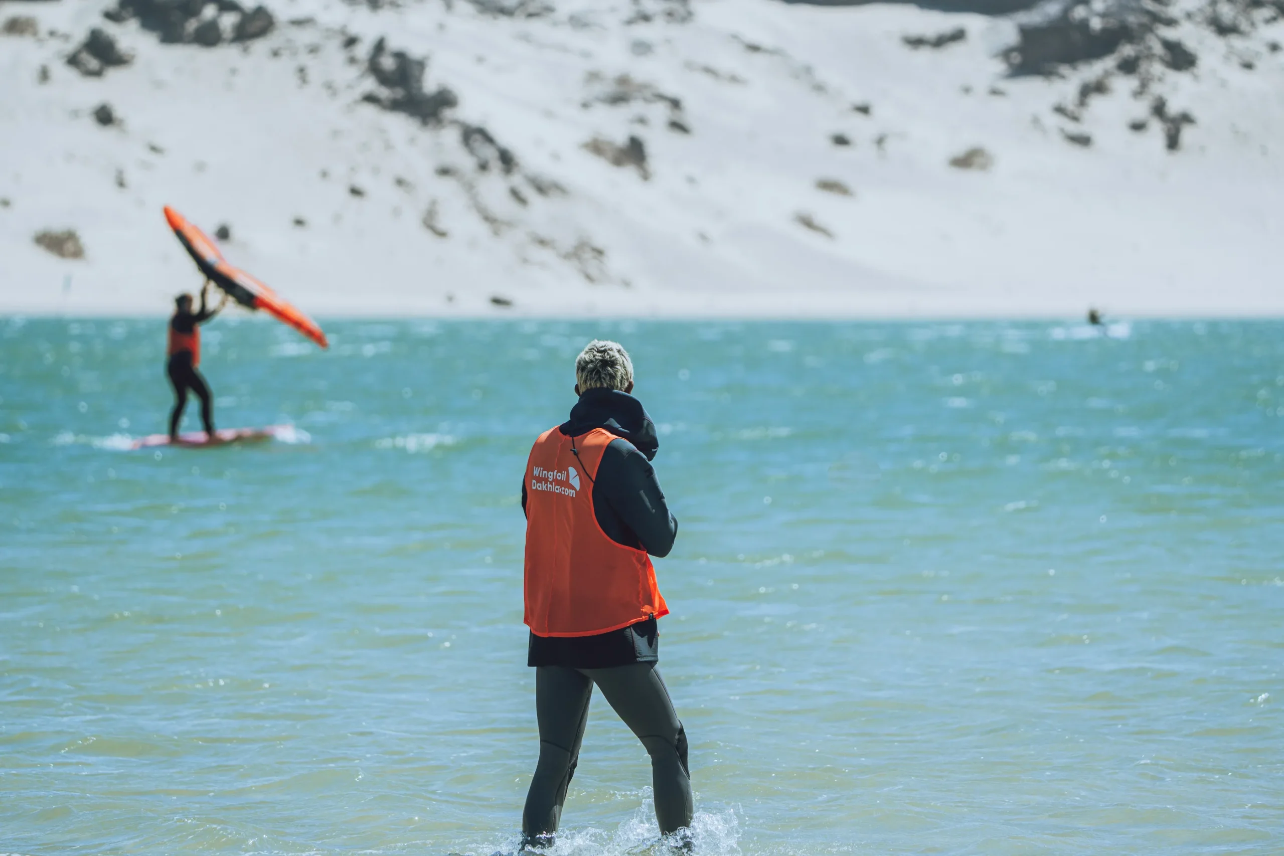 Cours de wingfoil à Dakhla avec casque radio – moniteur guidant un élève à distance dans la lagune