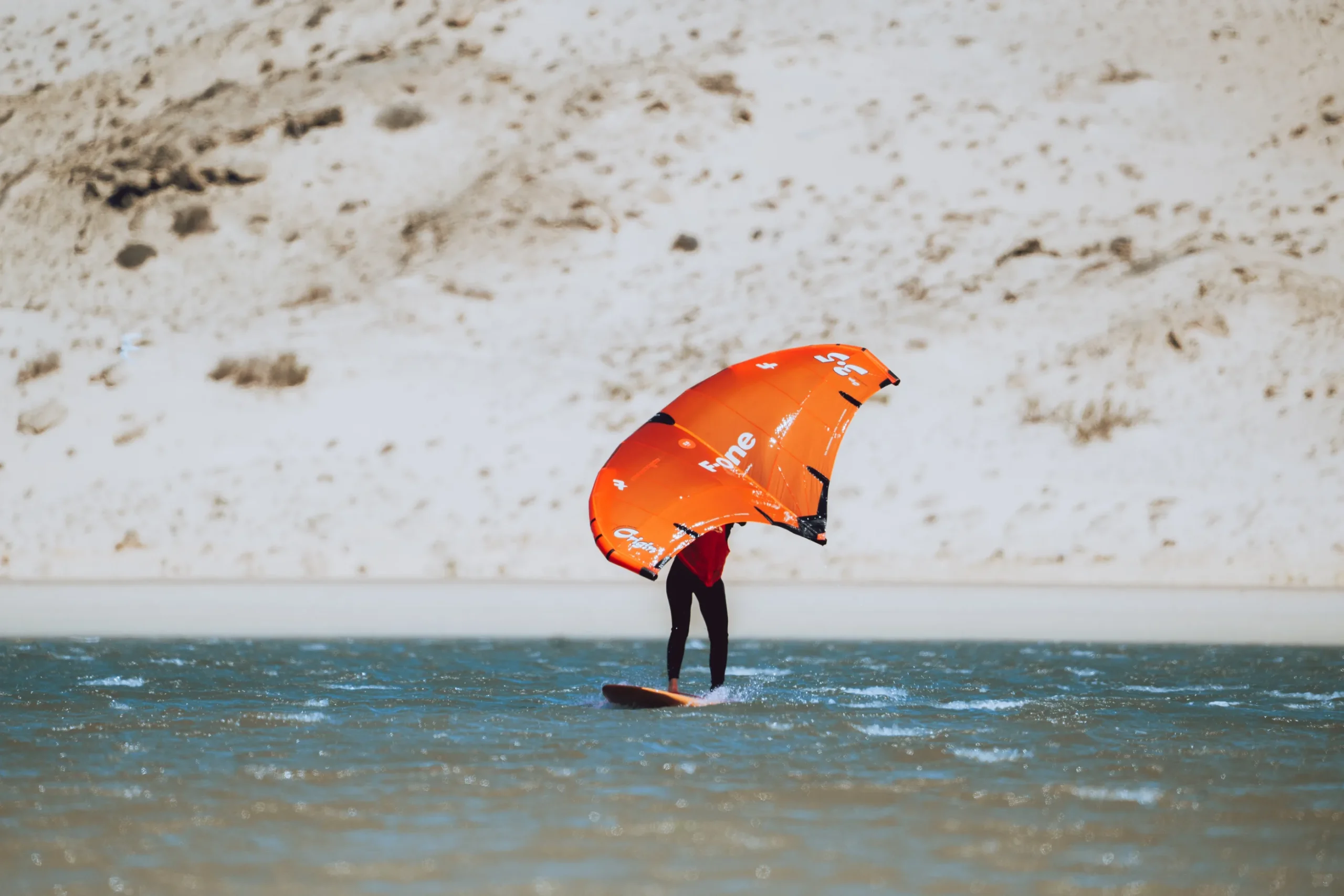 Navigation en wingfoil à Dakhla dans la lagune – rider contrôlant son aile sur eau turquoise
